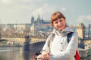 close-up portret van een jonge meisjestoerist die naar de camera kijkt en glimlacht, charles bridge karluv most over de rivier de vltava foto