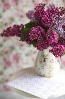 boeket van violet lila in een vaas. stilleven met bloeiende takken van sering in vazen. wenskaart mock-up. ruimte voor tekst. foto