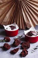 chocolademuffins in rode kopjes. kleine geglazuurde keramische ramekin met bruine cakes op een grijze en witte achtergrond. foto