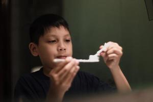 Aziatische jongen met tandenborstel en tandpasta die zich voorbereidt op het tandenpoetsen foto