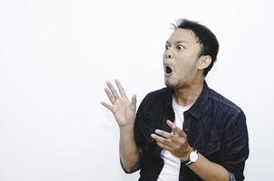 jonge aziatische man is verrast en schreeuwt wow met naar rechts te wijzen met zijn hand geïsoleerd op een grijze achtergrond. foto