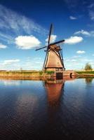 kleurrijke lentedag met traditionele Nederlandse windmolens kanaal in ro foto