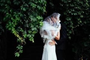 jonge bruid knuffelt haar bruidegom in prachtig park foto