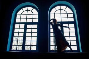 vrouw in vintage jurk binnen bij het raam