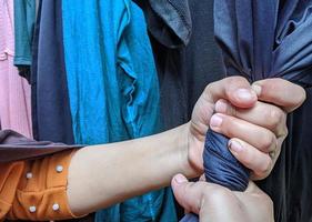 beide handen wringen kleren om snel te drogen. illustratie van het wassen en drogen van kleding voor huishoudelijke activiteiten. foto