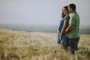 jonge man en zijn zwangere vrouw in het zomerveld foto