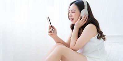 afbeelding van een jonge aziatische vrouw die 's ochtends thuis muziek luistert foto