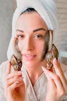 portret van jonge donkerharige vrouw met slakken achatina reus op haar gezicht foto