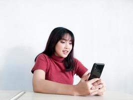 blij voelen en lachend gezicht van jonge mooie aziatische vrouw die op de smartphone kijkt. Indonesische vrouwen foto