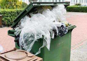 groene vuilnisbak vol met plastic verpakkingsafval foto