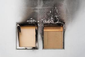 brand in huis of woning - dichtgetimmerde ramen en verbrande gevel van flatgebouw zwart door roet foto