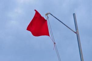 rode vlag teken van gevaar op zee over blauwe lucht foto