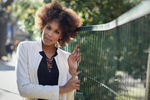 jonge zwarte vrouw met afro kapsel staande in stedelijke achtergrond foto