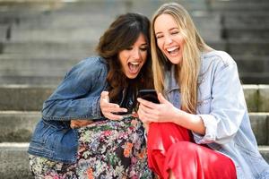 twee meisjes kijken naar iets grappigs op hun smartphone foto