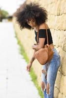 jonge gemengde vrouw met afrohaar die op straat staat foto