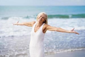 gelukkige volwassen vrouw die haar armen op het strand opent, haar vrije tijd doorbrengt, geniet van haar vrije tijd foto