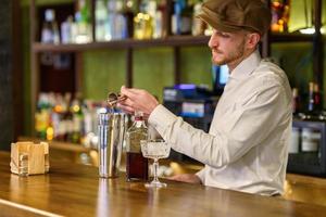mannelijke barkeeper die alcohol in shaker giet foto