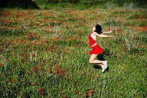 een meisje in het rood gekleed in een veld met klaprozen foto