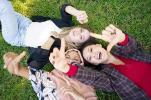 vrolijke dames gebaren camera terwijl liggend op gras foto