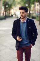 man in de straat in formalwear met smartphone in zijn hand. foto