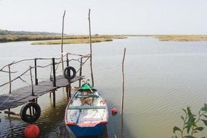 blauwe boot naast een houten pier. rijstvelden in de verte. alentejo, portugal, foto