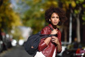 jonge zwarte vrouw met afro kapsel staande in stedelijke achtergrond foto
