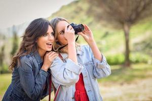 twee jonge toeristenvrouwen die buiten foto's maken foto