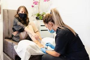 schoonheidsspecialiste die een pedicure geeft die de nagels van haar cliënt lakt in een schoonheidscentrum. foto