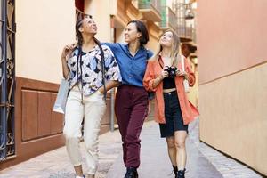 gelukkige multiraciale vrouwelijke beste vrienden die tijdens vakantie in de stad wandelen foto