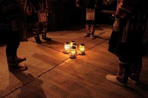 inheemse podiumkunsten aan toeristen. 's nachts zwak licht dansen akha bergstammen, gekleed in traditionele kostuums en prachtige ornamenten, ritmisch rond lantaarns, benen en voeten samen. foto