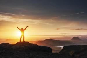 gelukkige man die bij zonsondergang op een klif staat foto
