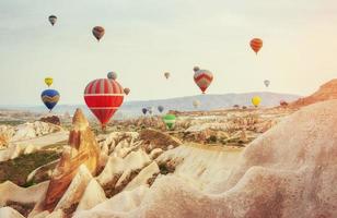 kleurrijke heteluchtballonnen die over rode vallei in cappadocië vliegen, foto