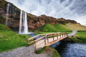 seljalandfoss waterval bij zonsondergang. brug over de rivier. fantasieën foto