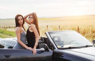 meisjes poseren voor de camera in een zwarte cabrio foto