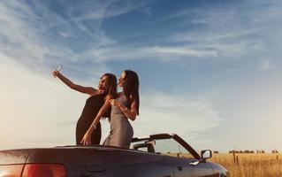 twee sexy brunette vrouw staande in de buurt van cabriolet op de weg foto