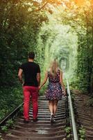 verliefde paar in een tunnel van groene bomen op de spoorweg foto