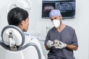 tandarts die aan een patiënt uitlegt hoe een tandheelkundige mal werkt in een tandheelkundige kliniek foto