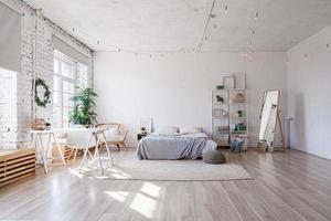 stijlvol loft slaapkamer interieur. ruim design appartement met lichte muren grote ramen groot bed. schone moderne inrichting met elegant meubilair in minimalistische scandinavische stijl. foto