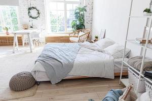 stijlvol loft slaapkamer interieur. ruim design appartement met lichte muren grote ramen groot bed. schone moderne inrichting met elegant meubilair in minimalistische scandinavische stijl. foto