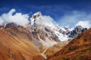 herfstlandschap en sneeuwbergen in prachtige cumuluswolken. foto