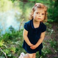 schattig klein blond meisje is tegen de achtergrond van water en g foto