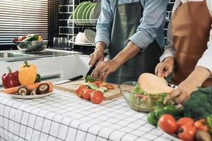 twee jonge aziatische stellen helpen elkaar en genieten van koken in de keuken. foto