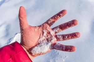 een man houdt een handvol verse sneeuw in een palm die in de winter is bevroren van de kou foto