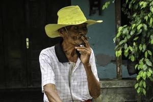 close-up portret van Aziatische Javaanse oude man met een sigaret in zijn hand foto
