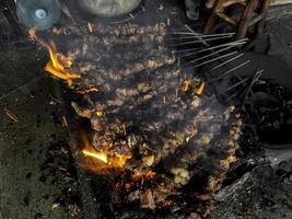 geit saté op rood vuur grillen door mensen. traditionele Indonesische gerechten gemaakt van schapenvlees. foto