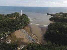 luchtfoto van baron beach in gunung kidul, indonesië met vuurtoren en traditionele boot. foto