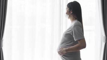 jonge zwangere vrouw die een beschermend masker draagt en een baby, gezond en moederschapsconcept verwacht foto