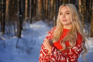 mooie gelukkige blonde vrouw in rode trui in het winterbos foto