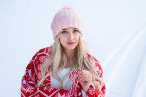 portret van een schattige vrouw tegen de sneeuw in een roze hoed en rode plaid poseren voor de camera foto