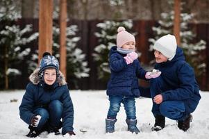 drie kinderen spelen in de winterdag. broers met jongste zus. foto